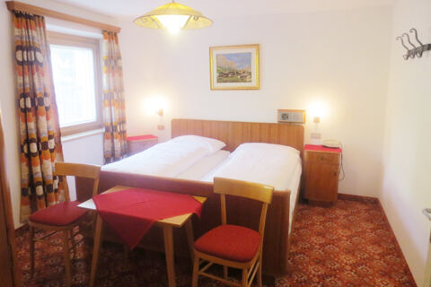 Room with double bed, wooden furniture, patterned curtains and carpet at Hotel Gasthof Borest & Residence Riposo