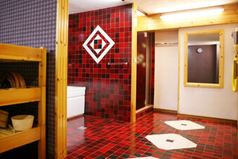 Room interior at Hotel Gasthof Borest & Residence Riposo with red and black tiled floor and walls, wooden shelves, and mirror