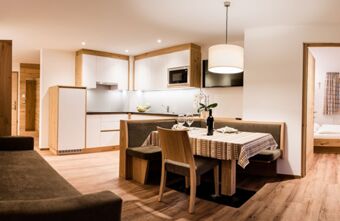 Modern kitchen and dining area with wooden furniture and white cabinets inside Residence Flamingo apartment room