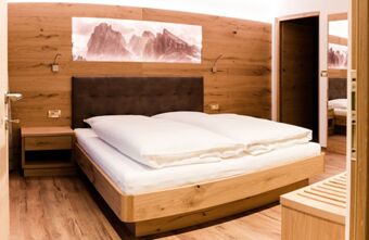 Double bed with white bedding, wooden walls and floor, nightstand, and mountain decor in Residence Flamingo room