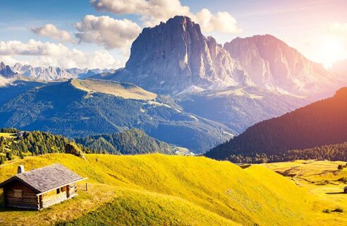&Scaron;irok&aacute; horsk&aacute; krajina se zelen&yacute;mi kopci, dřevěnou chatou v popřed&iacute; a slunečnou oblohou, viděn&aacute; nedaleko rezidence Flamingo.