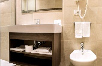 Kaasaegne vannituba koos valamu, bidee ja k&auml;ter&auml;tikutega Residence Flamingos, heledad plaadid ja puidust riiul valamu all.