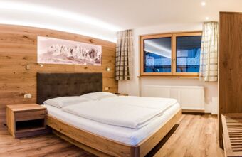 Bedroom at Residence Flamingo with wooden furniture, double bed, nightstand, window with curtains, and mountain artwork on wall