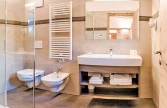 Modern bathroom in Residence Flamingo featuring a glass shower, toilet, bidet, sink with white towels, and wall-mounted heater