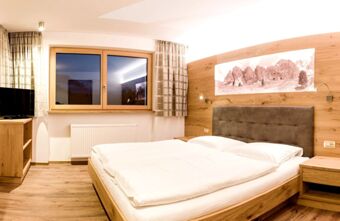 Bedroom in Residence Flamingo with large bed, wooden furniture, wall-mounted reading lights, and a window with curtains at night
