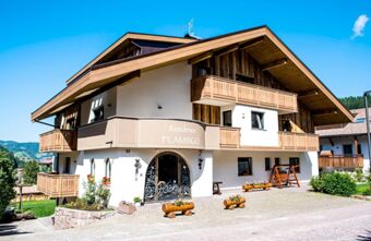Residence Flamingo features a multi-story chalet-style building with wooden balconies and flower planters under a clear blue sky