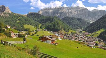 Green hills with scattered houses and cows, a village nestled in the valley under rocky mountains near Residence Flamingo