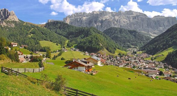 Green hills with scattered houses and cows, a village nestled in the valley under rocky mountains near Residence Flamingo