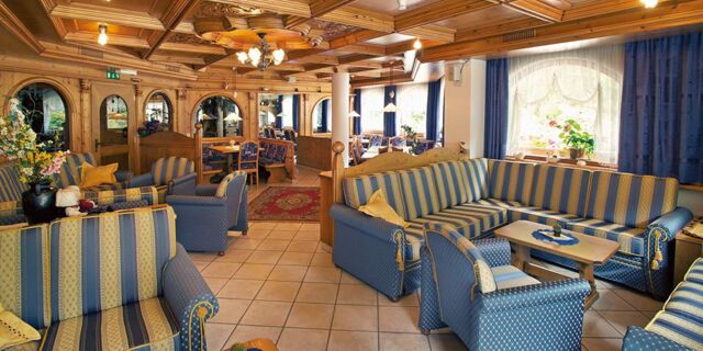 Hyggelig lounge med bl&aring;stribede sofaer og tr&aelig;m&oslash;bler i Hotel Schwarzenbachs traditionelle stil med naturligt lys.