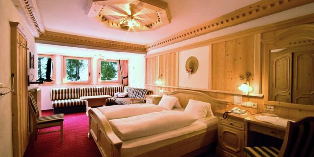 Hyggeligt hotelv&aelig;relse p&aring; Hotel Schwarzenbach med tr&aelig;paneler, dobbeltseng, opholdsomr&aring;de og r&oslash;dm&oslash;nstret t&aelig;ppe.