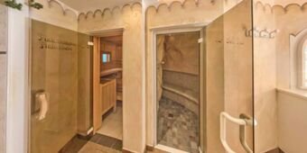 Inomhusomr&aring;de i Hotel Schwarzenbach med utsikt &ouml;ver en finsk bastu och ett saltvattensbad med kaklade b&auml;nkar och tr&auml;d&ouml;rrar.