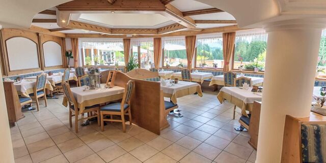 Lys og indbydende restaurant i Hotel Schwarzenbach med tr&aelig;m&oslash;bler, d&aelig;kkede borde og store vinduer med udsigt til naturen.