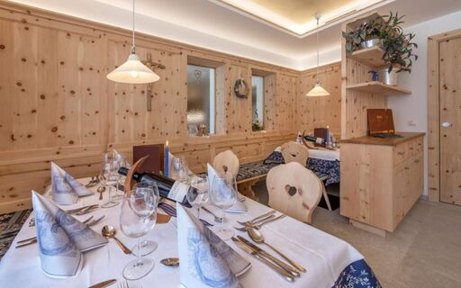Dining area with wooden panel walls, tables set with white and blue napkins, glassware, cutlery, and wine at Hotel Theiner