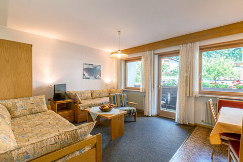 Living room with floral patterned couches, wooden furniture, a TV, and large windows in Residence Haus am Berg