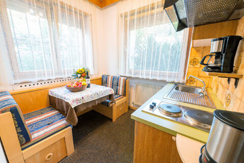 Kitchenette with electric stove, sink, coffee maker, and a corner dining area with a table at Residence Haus am Berg