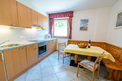 Kitchen area in Residence Haus am Berg featuring wooden cabinets, tiled floor, table with yellow cloth and corner bench seating