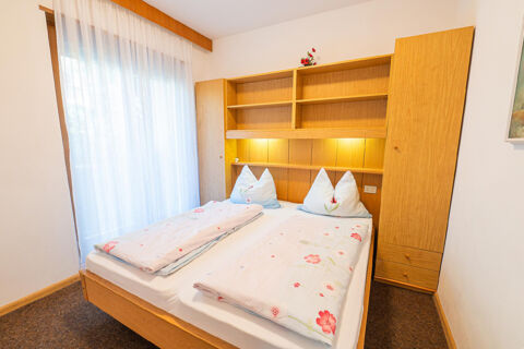 Double bed with floral bedding in a room featuring wooden shelves and cabinets at Residence Haus am Berg