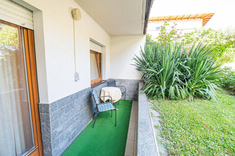 A balcony at Residence Haus am Berg with green flooring, two chairs, a table with cloth, and plants outside