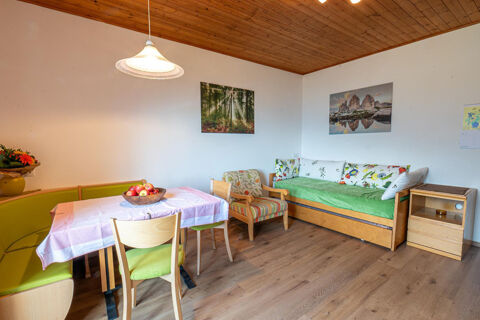 Dining area at Residence Haus am Berg with wooden furniture, a green cushioned bench, patterned pillows, and wall art