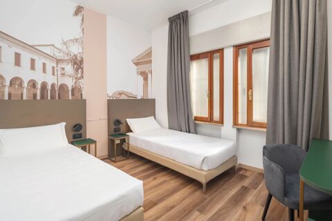Two single beds with white linens between green nightstands under a large mural in a room at B&B Hotel Treviso Al Fogher