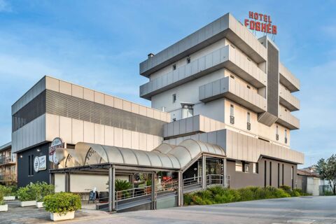 Modern multi-story building with covered entrance and balconies, featuring the Hotel Fogh&egrave;r sign at B&B Hotel Treviso Al Fogher