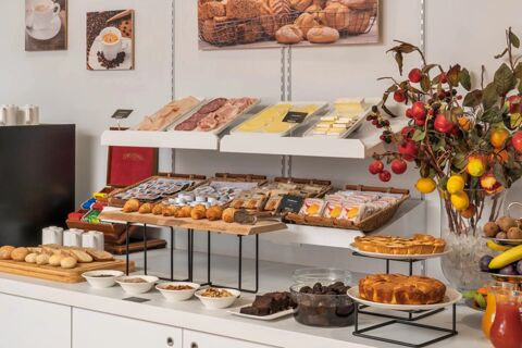 Breakfast buffet display at B&B Hotel Treviso Al Fogher featuring cold cuts, cheese, bread, pastries, and fresh fruits with condiments