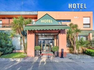Entrance of B&B Hotel Eurorest Conegliano with green awning, glass doors, potted plants, and palm trees in front of a peach building
