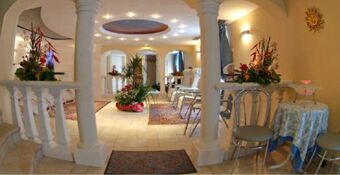 Jasne i eleganckie lobby w hotelu Torretta z białymi kolumnami, wygodnymi krzesłami, dekoracyjnymi dywanami i roślinami jako elementami wystroju.
