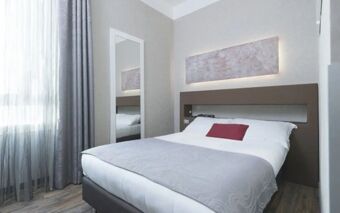 Minimalist hotel room at Hotel Atlantic with a double bed, gray curtains, a wall mirror, and abstract wall art above the headboard
