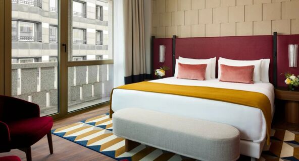 Hotel room at Tivoli Tivoli President Milano Hotel with a large bed, red headboard, mustard blanket, and floor-to-ceiling window
