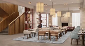Spacious lounge area with armchairs, round tables, modern hanging lights, and stairs at Tivoli Tivoli President Milano Hotel