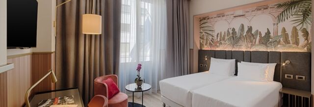 Hotel NH Collection Milano Touring room with twin beds, a floral mural above the headboard, a round table, and a window with sheer curtains