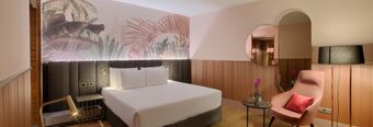 Hotel NH Collection Milano Touring room with a large bed, wall art, armchair, side tables, and a floor lamp