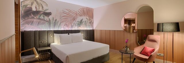 Hotel NH Collection Milano Touring room with a large bed, wall art, armchair, side tables, and a floor lamp