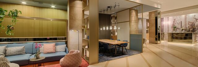 Modern hotel lobby with blue sofa, patterned armchairs, wooden table with blue chairs, and marble floor at Hotel NH Collection Milano Touring