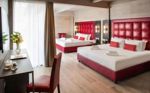 Two large beds with red headboards and white linens in a bright room featuring a desk and chair at Spice Hotel Milano