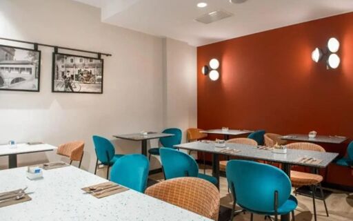 Dining area with granite tables, blue and orange chairs, and black and white photos on the wall at Hotel Canada
