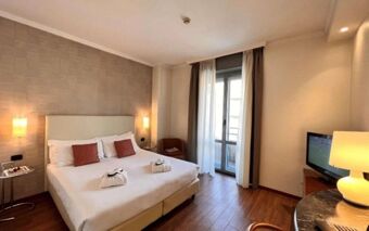 Hotel room at Best Western Hotel City with double bed, two bedside lamps, a TV, a chair, and balcony doors visible