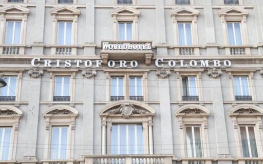 Facade of a stone building displaying large letters and a sign for Hotel Cristoforo Colombo and Worldhotel above several windows