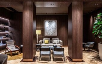 Interior view of a lounge area at Hotel Cristoforo Colombo with wood panel walls, modern furniture, and decorative artwork