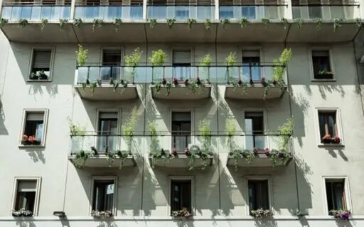 Facade of Ostello Bello Grande Hostel with multiple windows, glass balconies, and green plants on each balcony