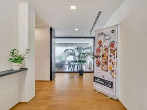 Bright hallway with wooden floor and potted plants next to a B&B Hotel Milano Portello breakfast advertisement banner