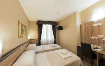Hotel Brianza room with two single beds, beige walls, a window with dark curtains, a desk with a chair, and a wall-mounted TV