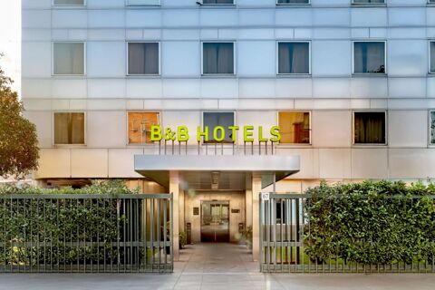 Facade of B&B Hotel Torino President with several large windows and green B&B Hotels sign above the entrance gate and hedge