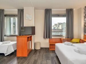 Two beds with white linens and folded towels are in a cabin with windows, gray curtains, and wooden furniture at B&B Hotel Torino President