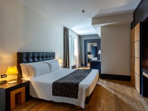 Room with a large bed, bedside tables with lamps, a wardrobe, and a mirror in the B&B Hotel Borgaro Torinese