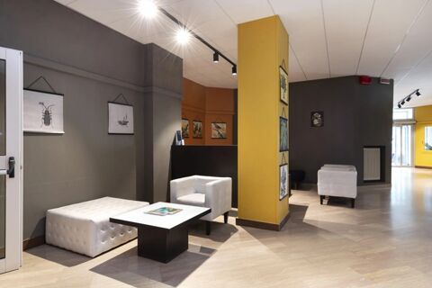 Modern hotel lobby area at B&B Hotel Como City Center with white armchairs, tufted benches, framed wall art, and overhead lighting