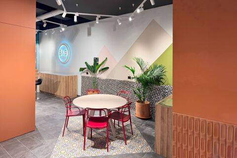 Round dining table surrounded by red chairs on patterned floor tiles with plants near a wall at B&B Hotel Como Baradello