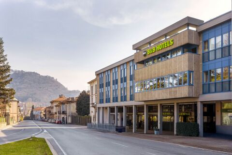Modern beige and blue building with a green B&B Hotels sign on the facade along a quiet street near hills B&B Hotel Como Baradello