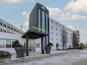 Modern white and black building with tall windows and green B&B Hotels sign at entrance of B&B Hotel Quarto D'Altino